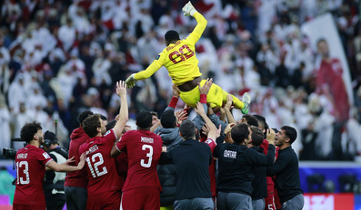 Qatar's players and officials toss goalkeeper Meshaal Barsham in the air after the victory at Al Bayt Stadium